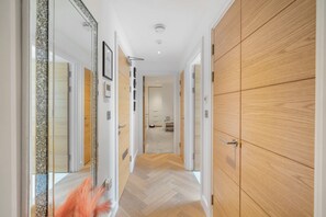 Stylish hallway with a herringbone-patterned floor, large mirror, and wooden paneling.