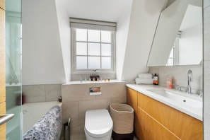 Bathroom features a large window, white sink, and a toilet, with ample storage for toiletries.