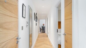 A hallway with wooden paneling on the walls, a mirrored closet door, and a dining area in the distance. - Marble Arch Penthouse 73, Best Location! (Greater London)