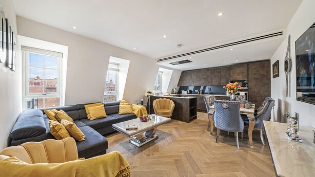 Uma sala de estar moderna com sofá, mesa de centro e área de jantar com cadeiras.