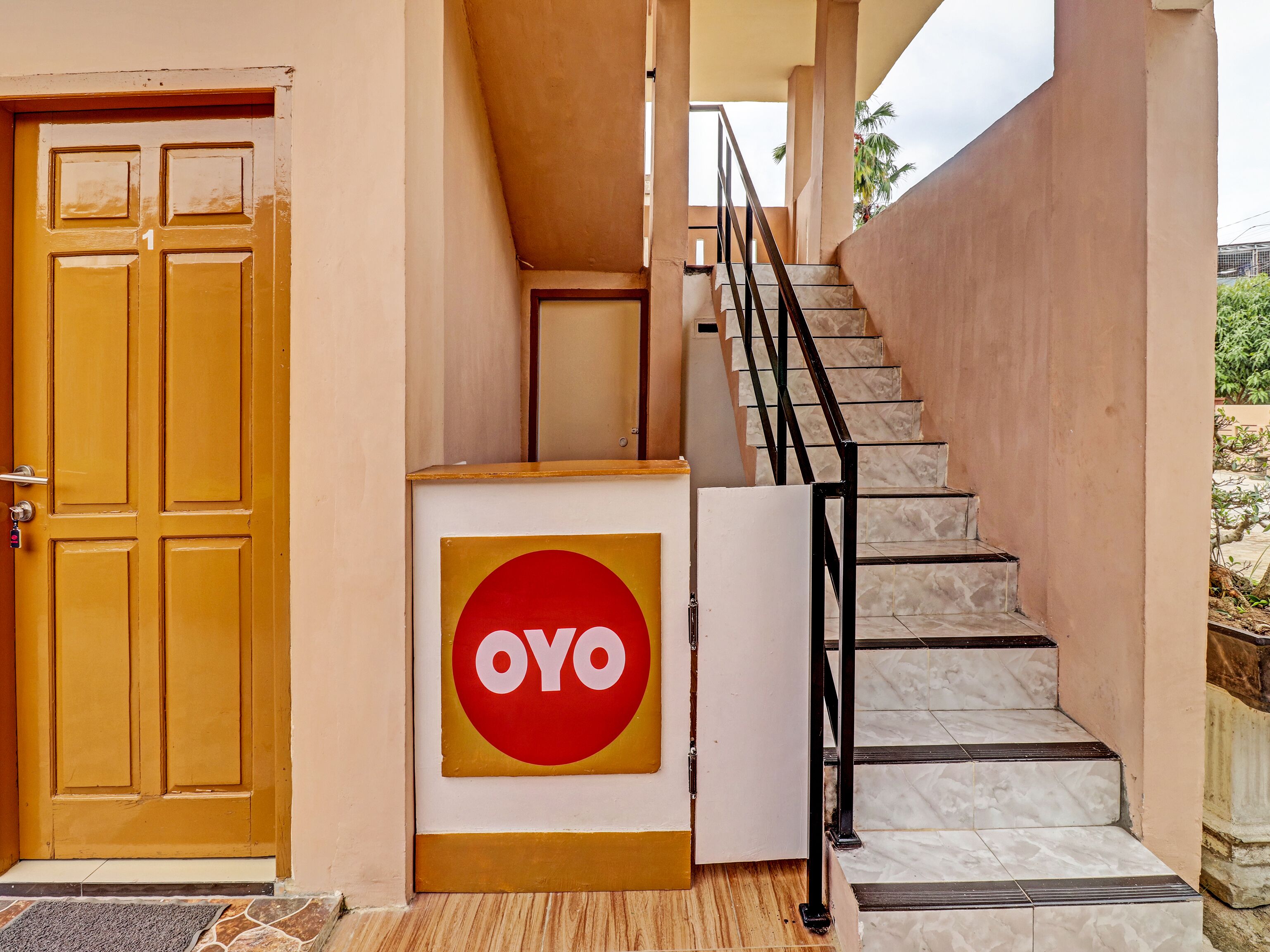 Una escalera con barandilla, una puerta con un número y un letrero con la palabra "OYO".