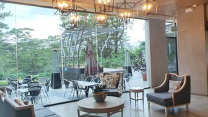 Un espacio interior amplio con mobiliario moderno, ventanas grandes y lámparas colgantes.