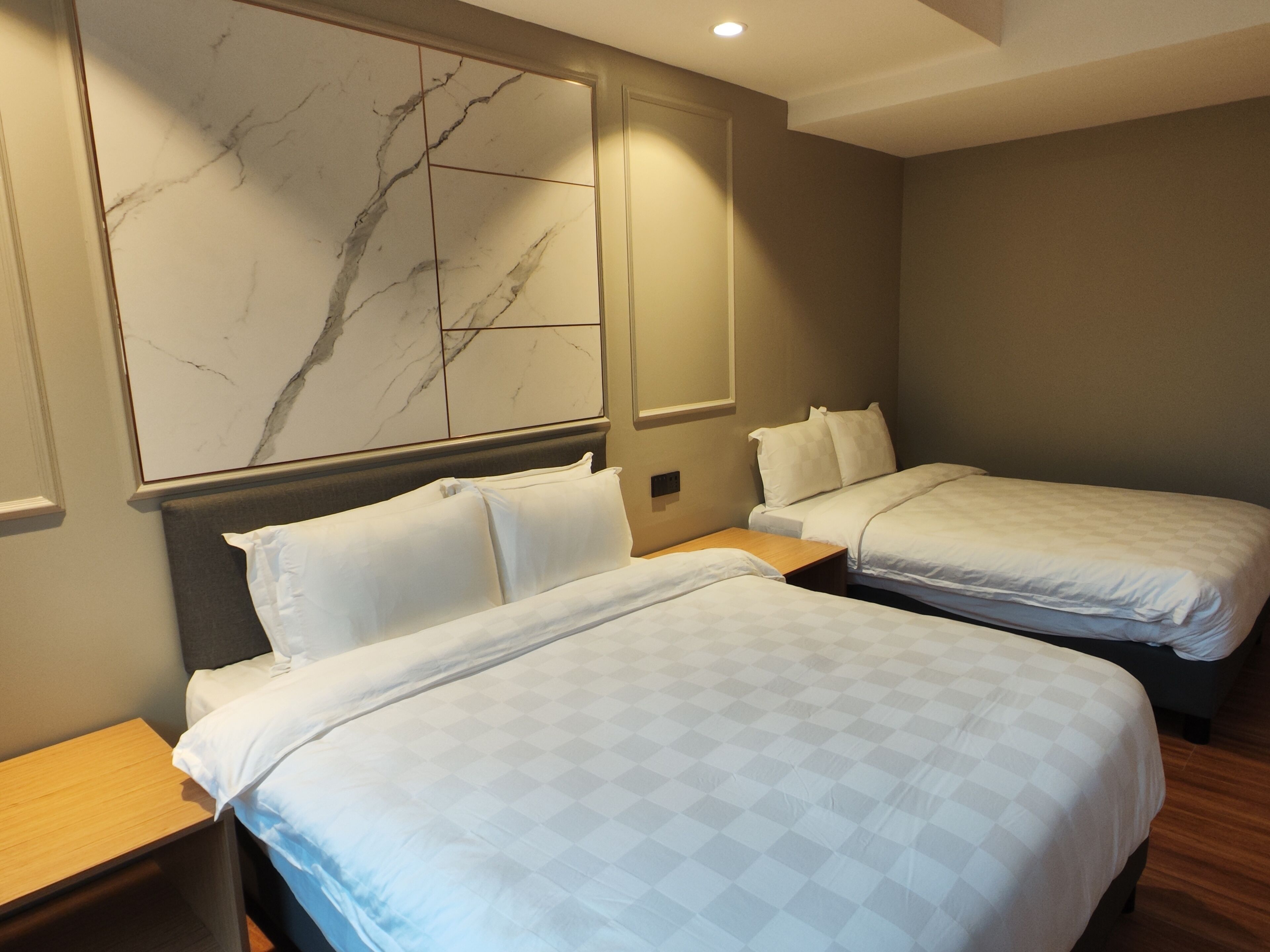 A hotel room with two beds, a large marble wall art piece, and a wooden nightstand.