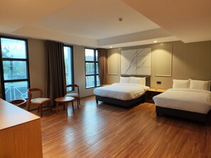 Habitación de hotel con una cama grande, otra más pequeña, un escritorio, una silla y vistas al exterior.