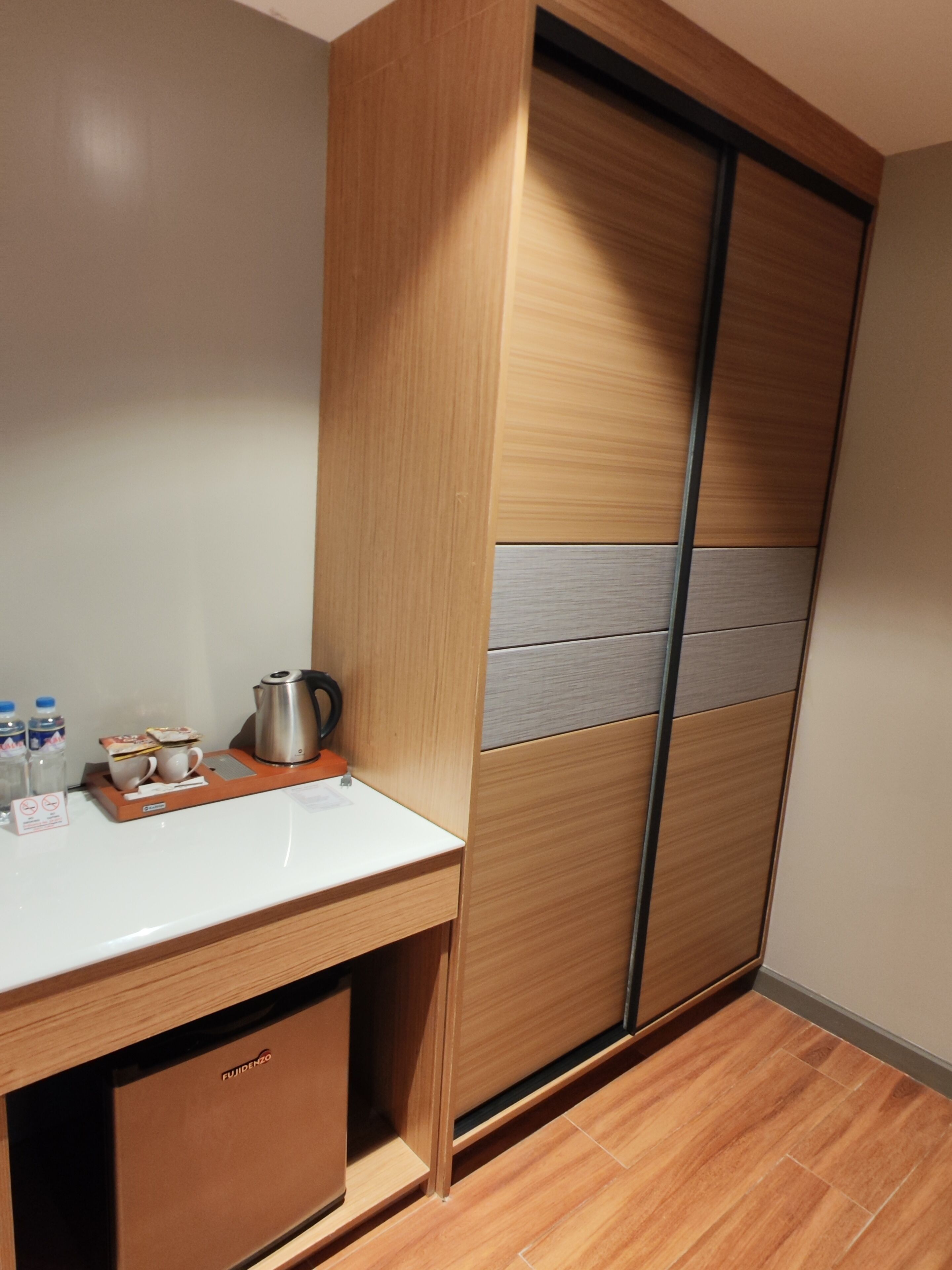 A modern room with a wooden wardrobe, a white countertop, and a small cabinet.