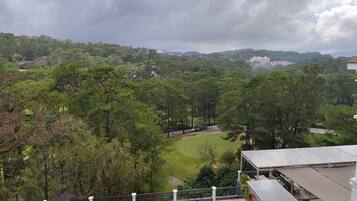 A rooftop terrace with outdoor seating, a view of a golf course, and surrounding greenery.