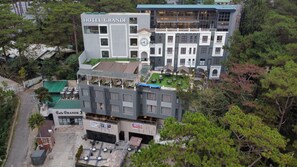 Un hotel de varios pisos con un llamativo letrero que dice 'HOTEL GRANDE', zonas de estar al aire libre y una terraza en la azotea.