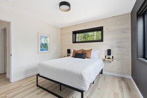 A bedroom with a bed, a window, a wall-mounted shelf with speakers, and a framed picture on the wall. - Ultimate Cabin Retreat, Sauna, Firepit, Fireplace (Crosby)