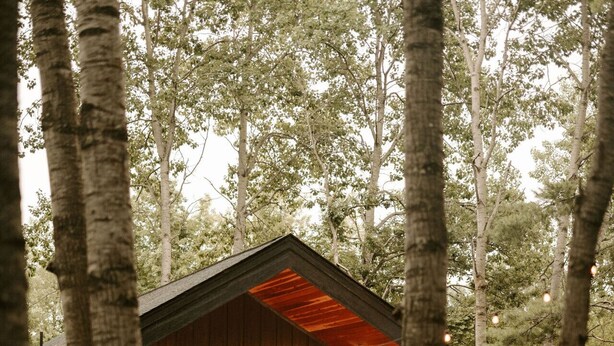 A rustic cabin with a wooden exterior, a covered porch, and a fire pit area.