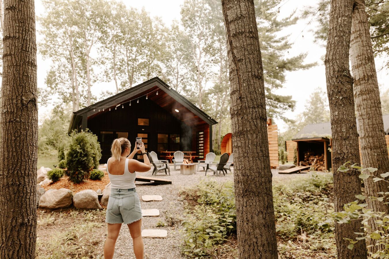 A cabin with a deck and outdoor seating, surrounded by trees.