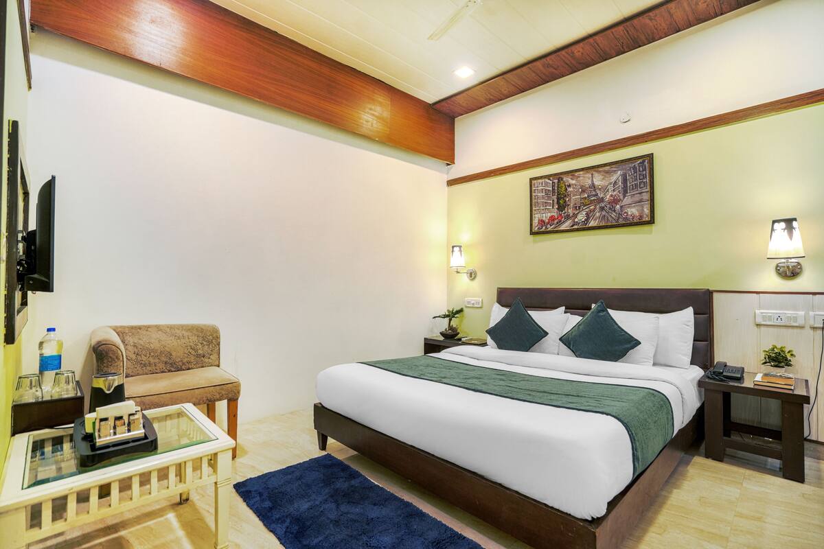 Une chambre d’hôtel bien rangée, avec un lit, un canapé, une petite table et un téléviseur.