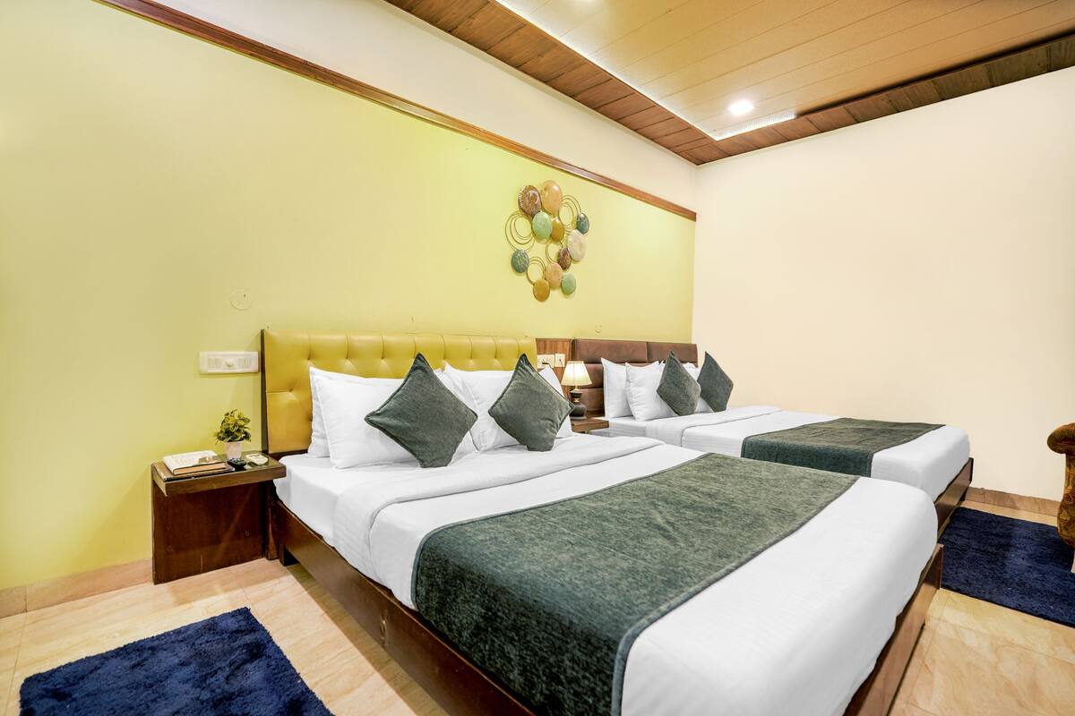 Une chambre d’hôtel avec deux lits, un plafond en bois, un élément décoratif mural et une petite table de chevet avec une lampe.