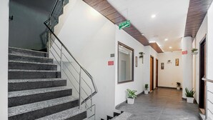 A modern hotel lobby with a staircase, a sign indicating an exit, and potted plants along the walkway. - Hotel Seven - Centre of City Chandigarh (Chandigarh)
