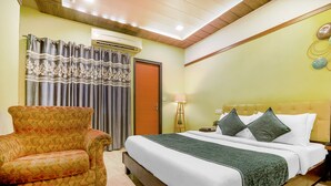 A bedroom with a bed, a chair, a lamp, and a door. - Hotel Seven - Centre of City Chandigarh (Chandigarh)