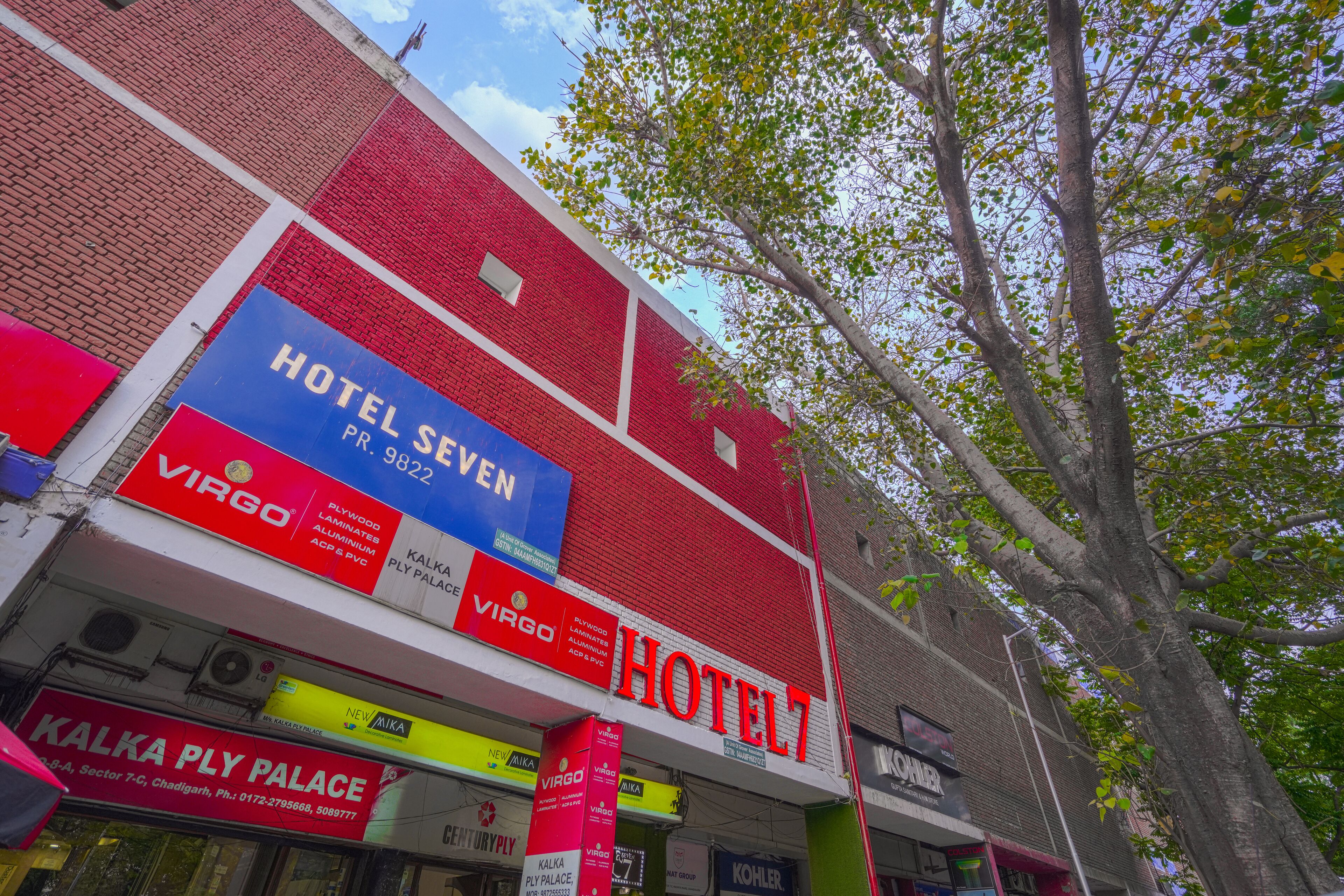 A hotel with a prominent red and white facade, multiple advertisements for brands like Virgin and New Balance, and a visible sign for 'Hotel Seven'.