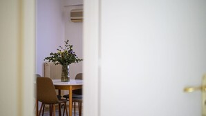 A dining area with a round table, chairs, and a vase with flowers. - Anna’s apartment Historic Center (Kalamata)