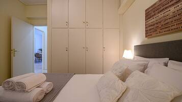 A hotel room with a bed, pillows, a folded towel, a wardrobe, and a wall with text.