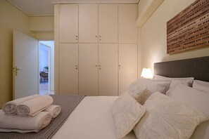 A hotel room with a bed, pillows, a folded towel, a wardrobe, and a wall with text.