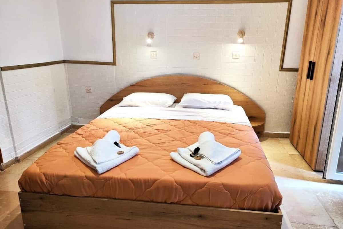 A hotel room with a wooden bed, white walls, and a white brick accent wall.