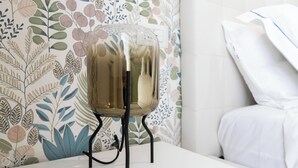 Une chambre avec un lit, un oreiller blanc et un mur décoratif orné de motifs de feuilles.