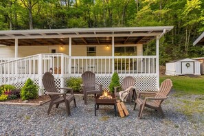 A covered outdoor seating area with Adirondack chairs and a fire pit. - Magical Location on the River, Hiking, and Rafting (Sylva)