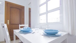 Un coin repas avec une table blanche dressée pour deux personnes, des bols bleus et des couverts.