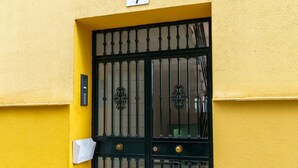Un bâtiment jaune avec un portail en métal noir et une boîte aux lettres.