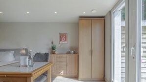 Une chambre à coucher moderne, avec un lit, une table de chevet, une lampe et une grande armoire.
