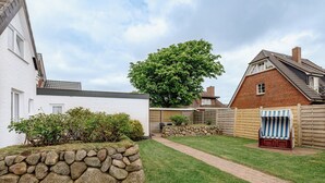 Un jardin avec un mur en pierre, une pelouse verdoyante, une clôture en bois et un espace détente abrité.