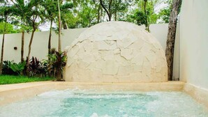 Un espace avec un bain à remous, agrémenté d’un mur en pierre et d’une végétation luxuriante.