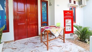 Entrada d'hotel amb una porta vermella, una taula amb una estovall d'estil i un rètol informatiu.