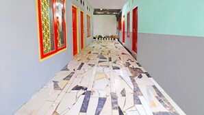 Un passadís amb terres de rajoles estampades, portes d'estructura vermella i plantes en testos.