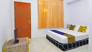 Una habitació amb un llit, una porta de fusta i una finestra amb cortines.