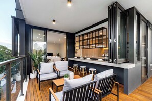 Una zona relax esterna moderna con un patio in legno, posti a sedere e un bancone cucina.
