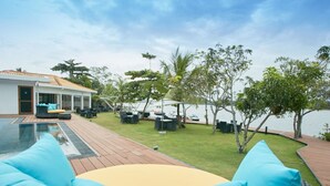 Un área junto a la piscina con sillones de descanso, piscina y vista al agua.