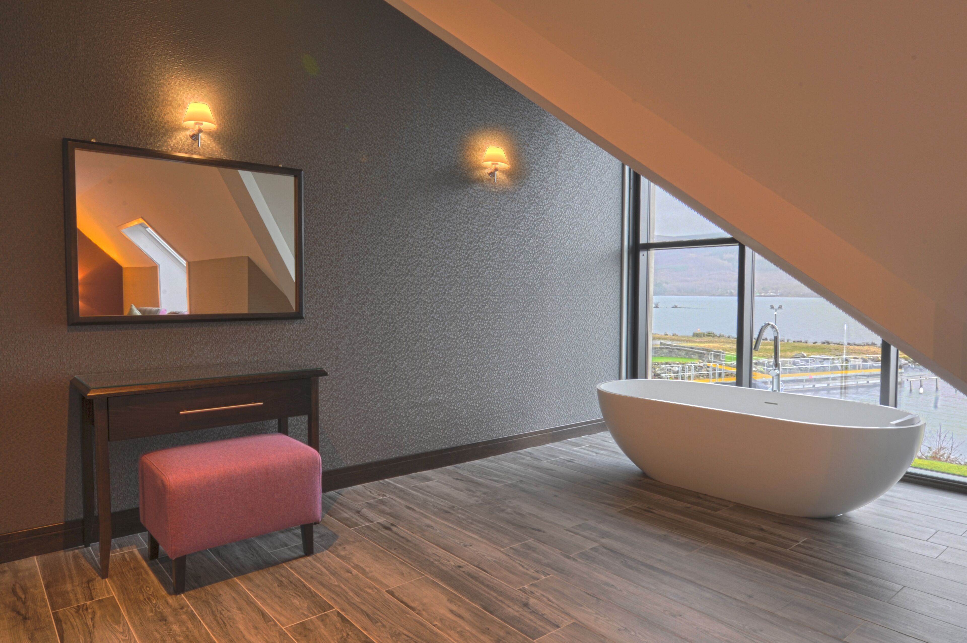 A modern bathroom with a freestanding bathtub, a bench, and a large mirror.