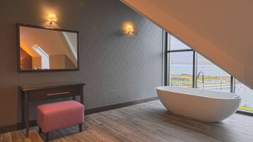 A modern bathroom with a freestanding bathtub, a bench, and a large mirror.