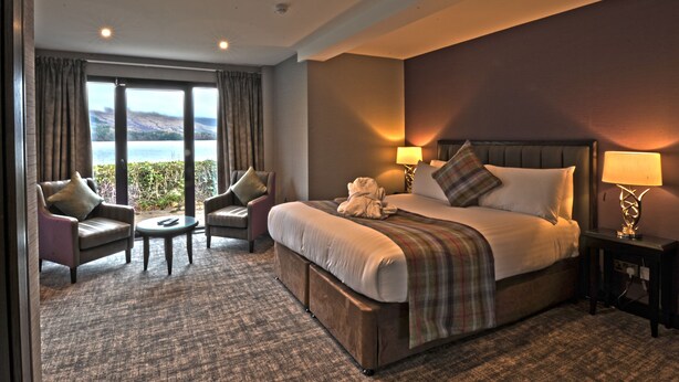 A hotel room with a large bed, two armchairs, a small table, and a view of the sea. - The Beach House (Alexandria)
