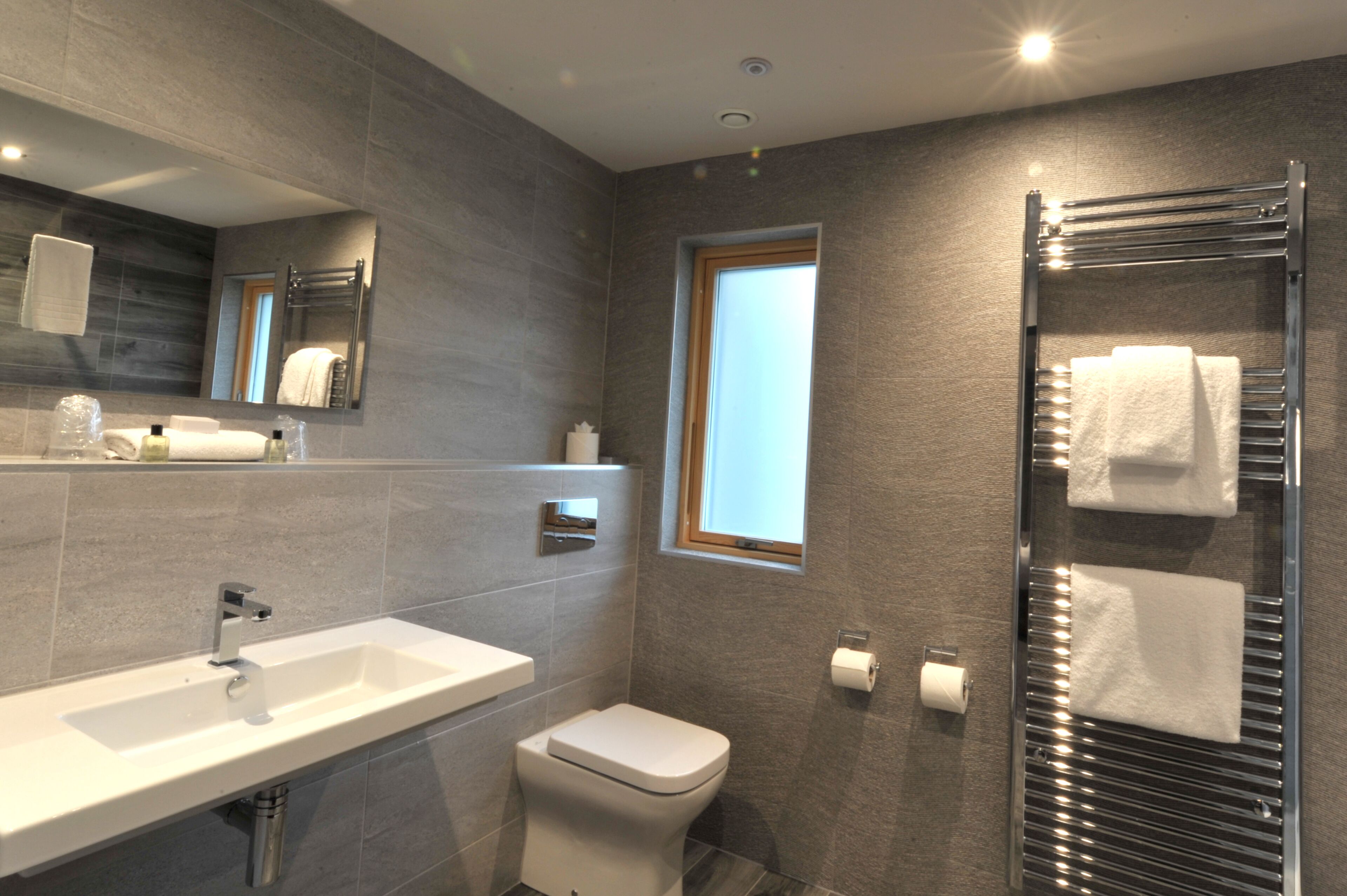 Un baño moderno con un lavamanos grande, inodoro y perchero.