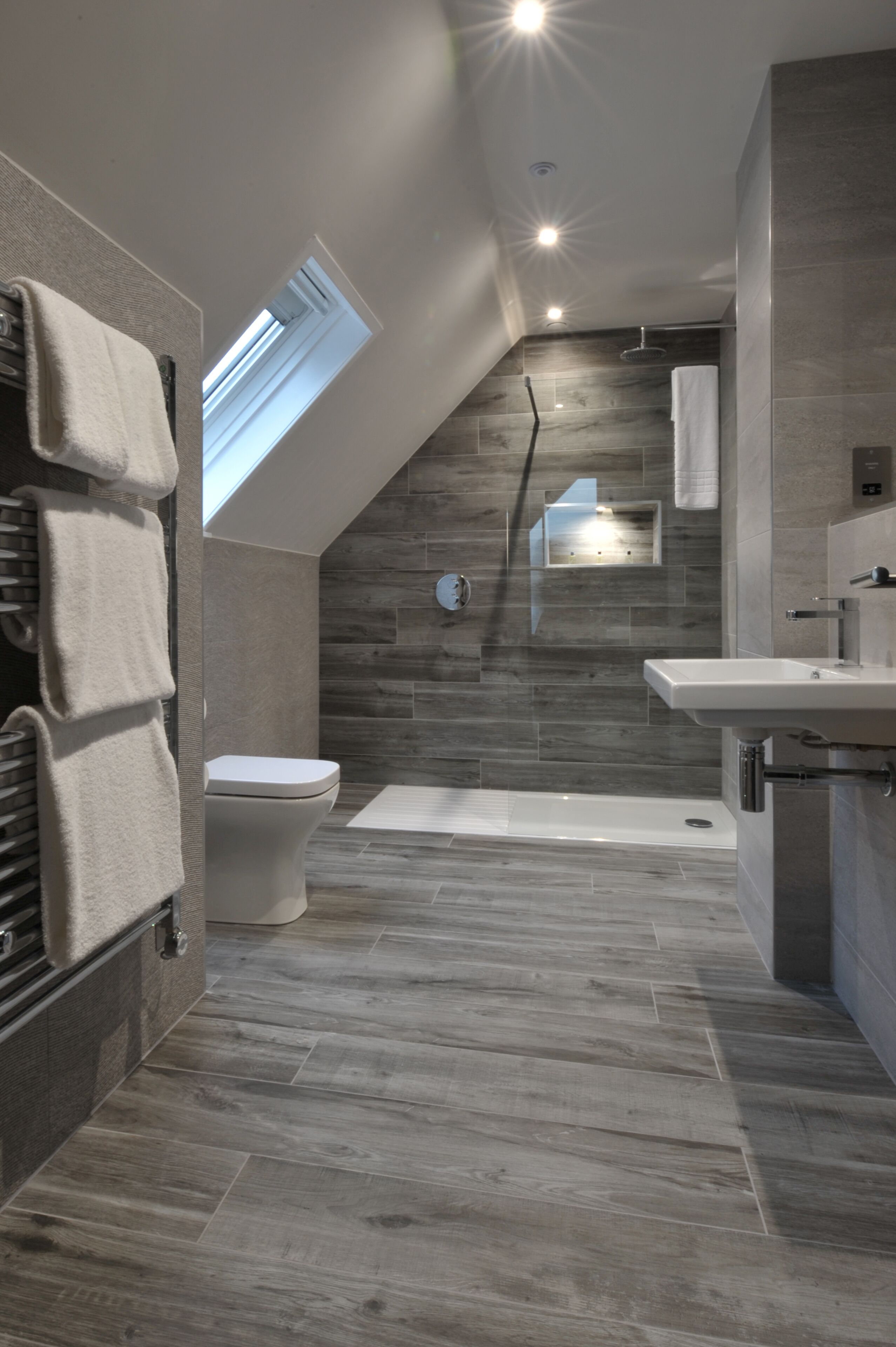 Un baño moderno con tragaluz, inodoro, bañera y lavamanos.
