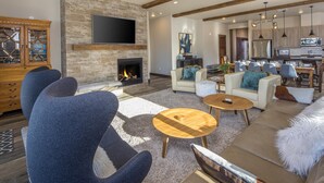 A modern living room with a fireplace, sofas, and a TV. - Penthouse | Close to Shuttle | Hot Tub (Big Sky)