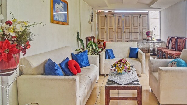 A living room with a sofa, armchairs, a coffee table, and a painting on the wall. - Hotel O Susupuan KostNearTaman Deki Lestari (Tondano)