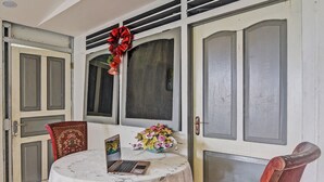 A room with a round table, two chairs, a laptop, a vase with flowers, and a red bow decoration on the door. - Hotel O Susupuan KostNearTaman Deki Lestari (Tondano)
