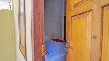 Un estrecho umbral da paso a una habitación con una cama y una ventana.