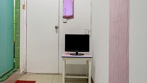 A small room with a white door, a table with a black monitor, and a red mat on the floor. - Hotel O Zazezo Homestay Syariah (Tanjung Pinang)