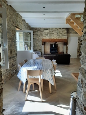 Un comedor con una mesa preparada para cuatro personas, rodeado de paredes de piedra y una escalera de madera.