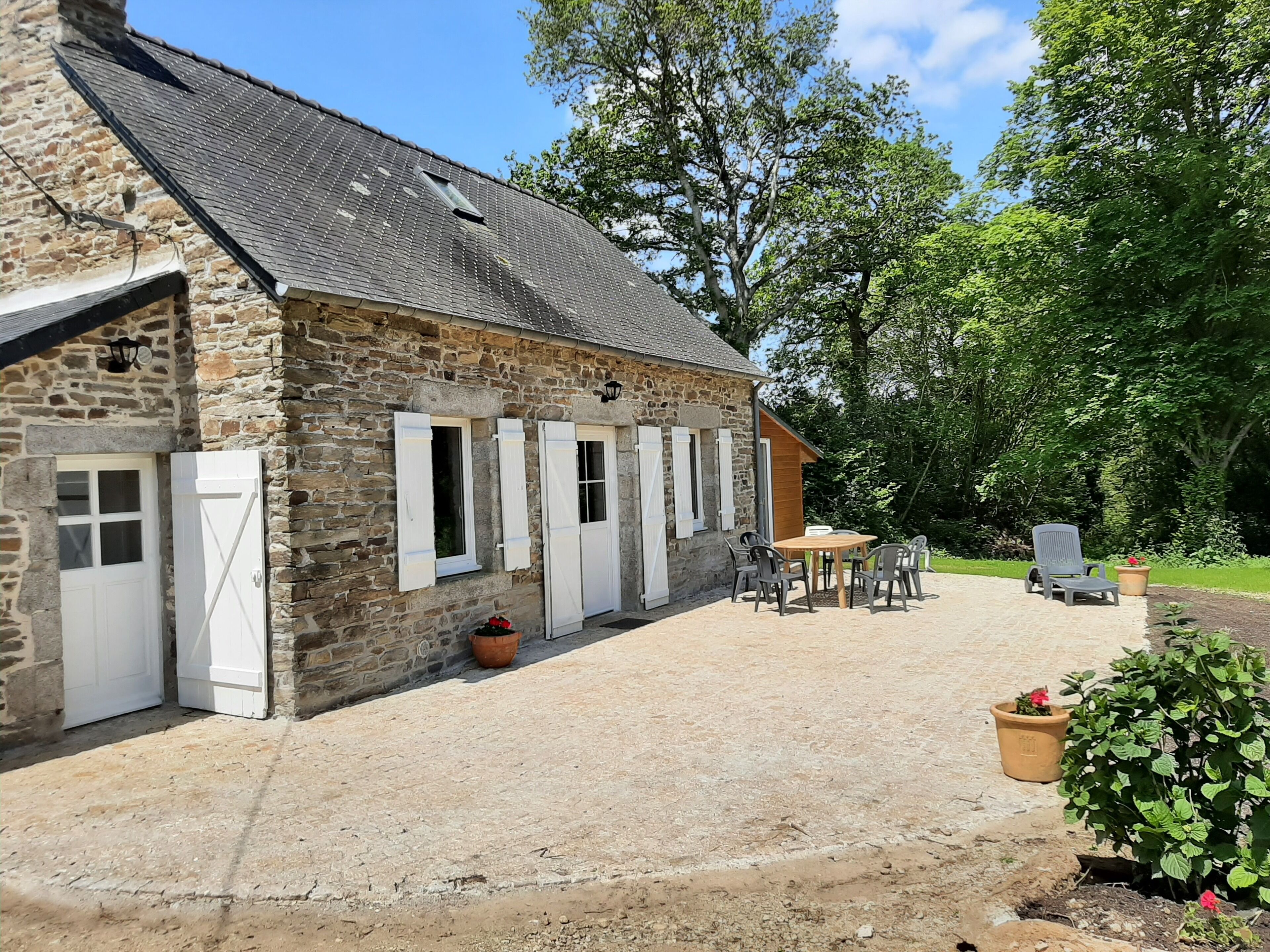 A stone building with a gravel patio, outdoor seating, and a garden area.