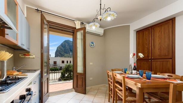 A kitchen with a dining area, a view of mountains, and a balcony.