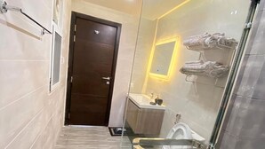 A modern bathroom with a glass shower enclosure, a toilet, and a sink. - Luxurious Apartment with Fascinating Margalla View (Islamabad)