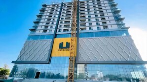 A high-rise building with a distinctive yellow sign reading "ELYSIUM" and a modern architectural design. - Luxurious Apartment with Fascinating Margalla View (Islamabad)